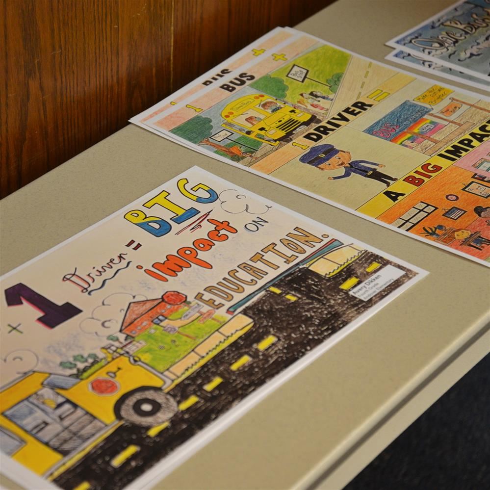 Posters from a previous transportation poster contest displayed on a table