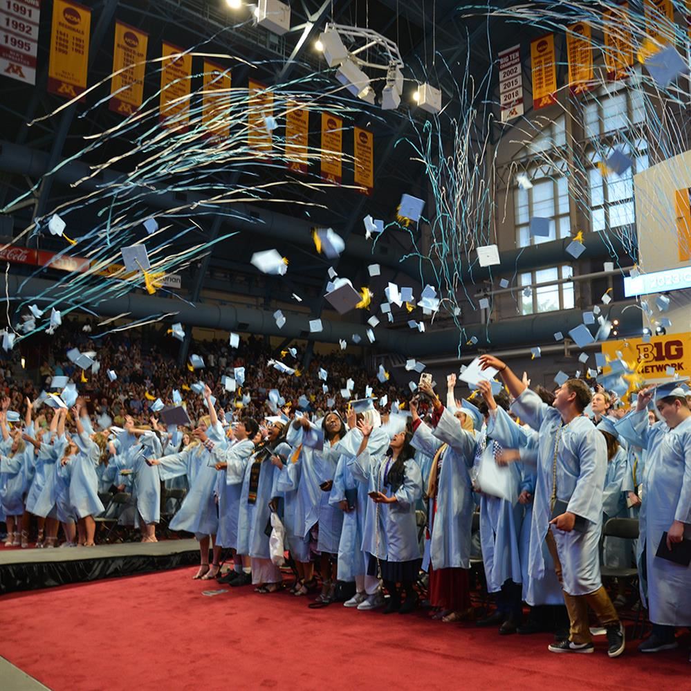 Blaine High School graduates toss their caps into the air as confetti flies above their heads 