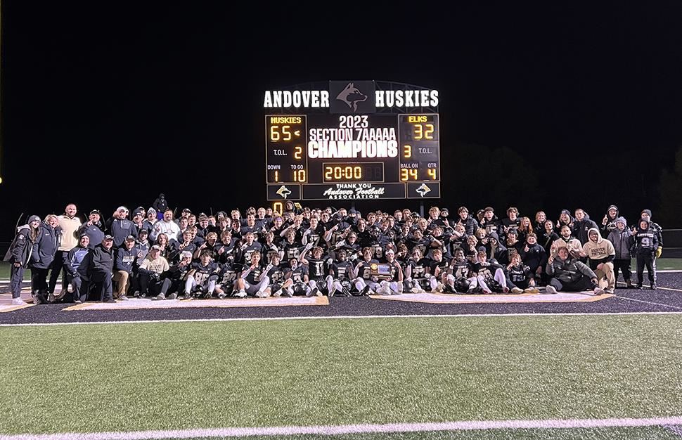 Andover High School football team pictured in front of scoreboard with the section championship trophy