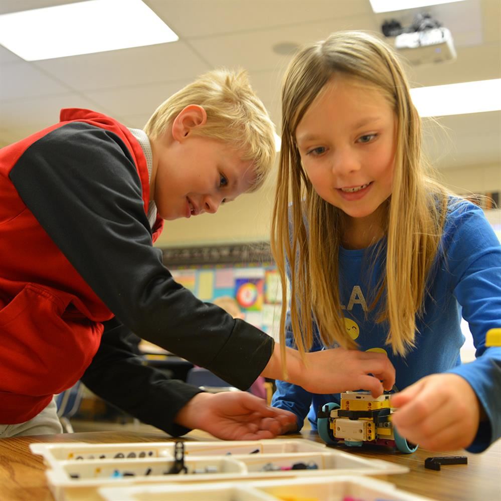  two students using LEGO kit to built robot