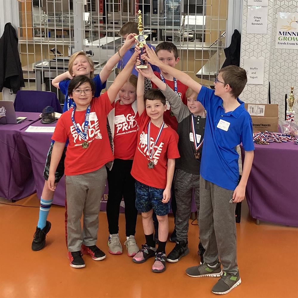  students gathered and holding a trophy over their heads