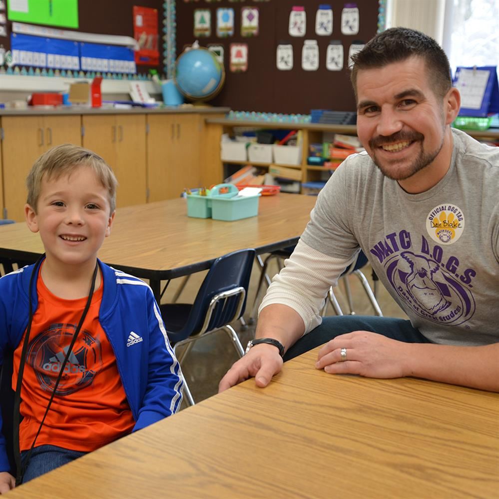  smiling father and student at a table in a classroom