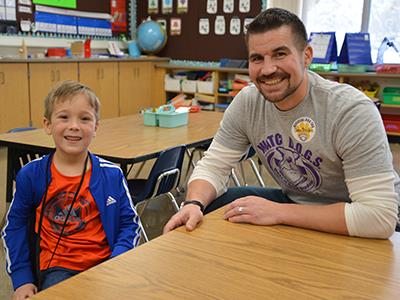 smiling father and son at a table in a classroom