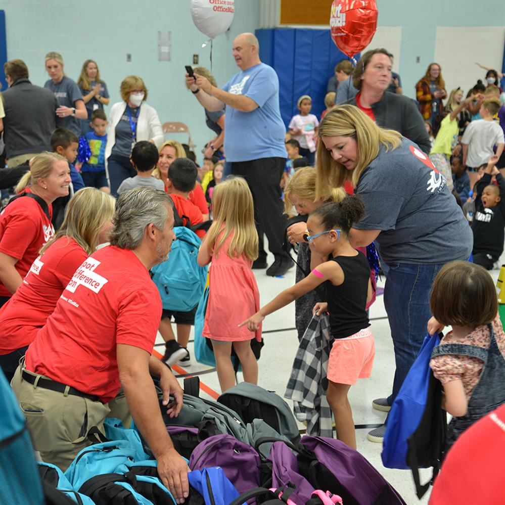 Students at Monroe Elementary School receive backpacks from Office Depot at event Sept. 9