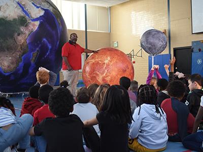 inflatable earth, sun and mars with students looking on