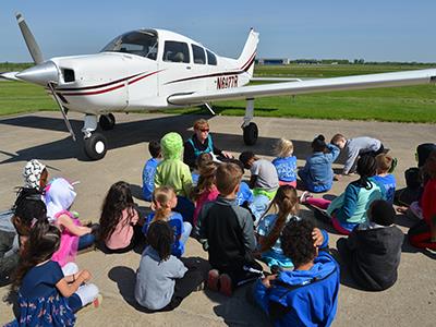 Students sitting in front of a plane