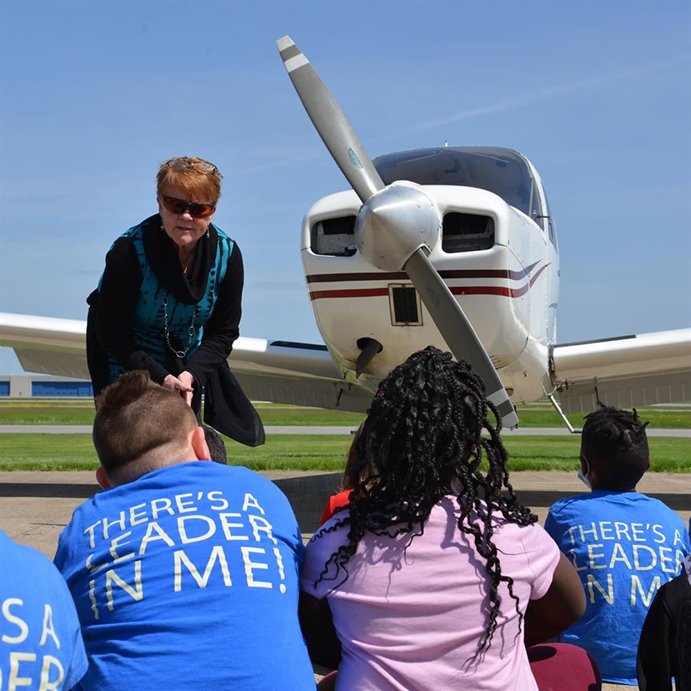  Pilot talking to kids with a plane behind her