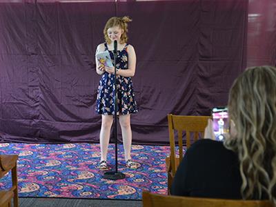 girl at a microphone reading poem for family