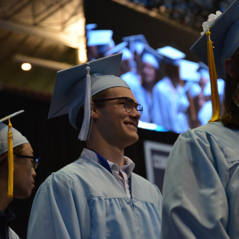 Close up of a student on graduation day wearing blue cap and gown