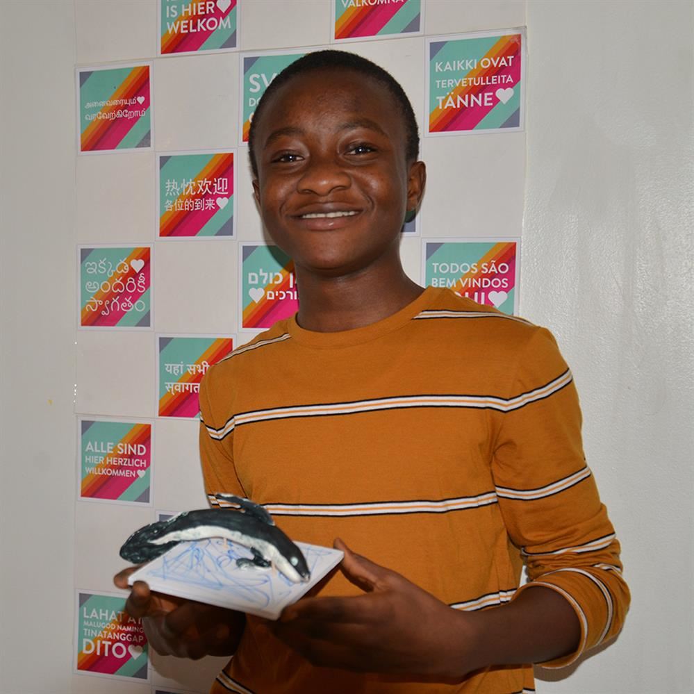  student holding his clay creation 