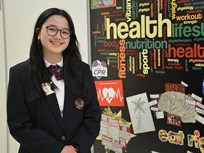 Phan posing for photo with health related words and pictures in the background 