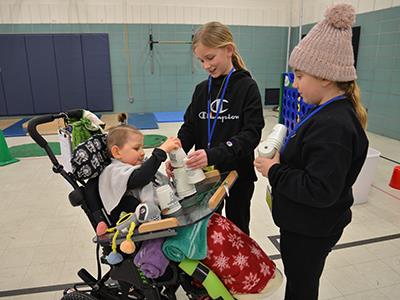 three students interacting, one student is in a wheelchair
