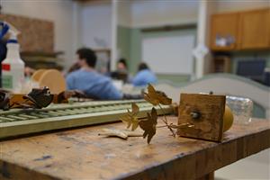 pieces of home decor on a worktable with students in the background 