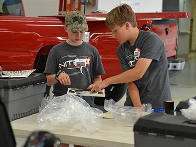 two students working together on stickers to detail the body of a car