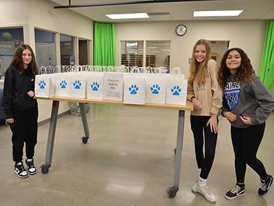 three students pose with multiple bags of preschool kits