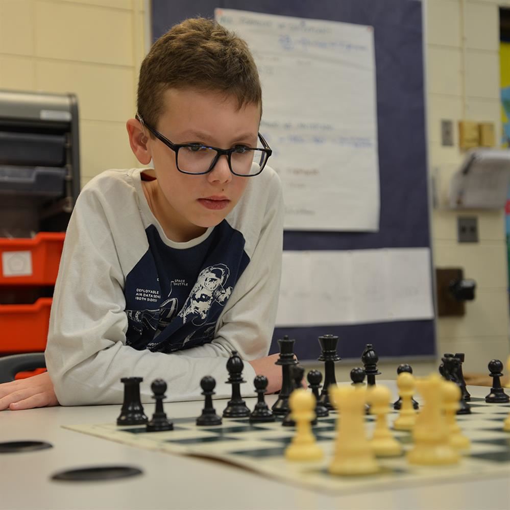  student looking at chessboard 