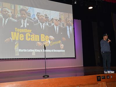 man on stage with MLK graphic on screen behind him