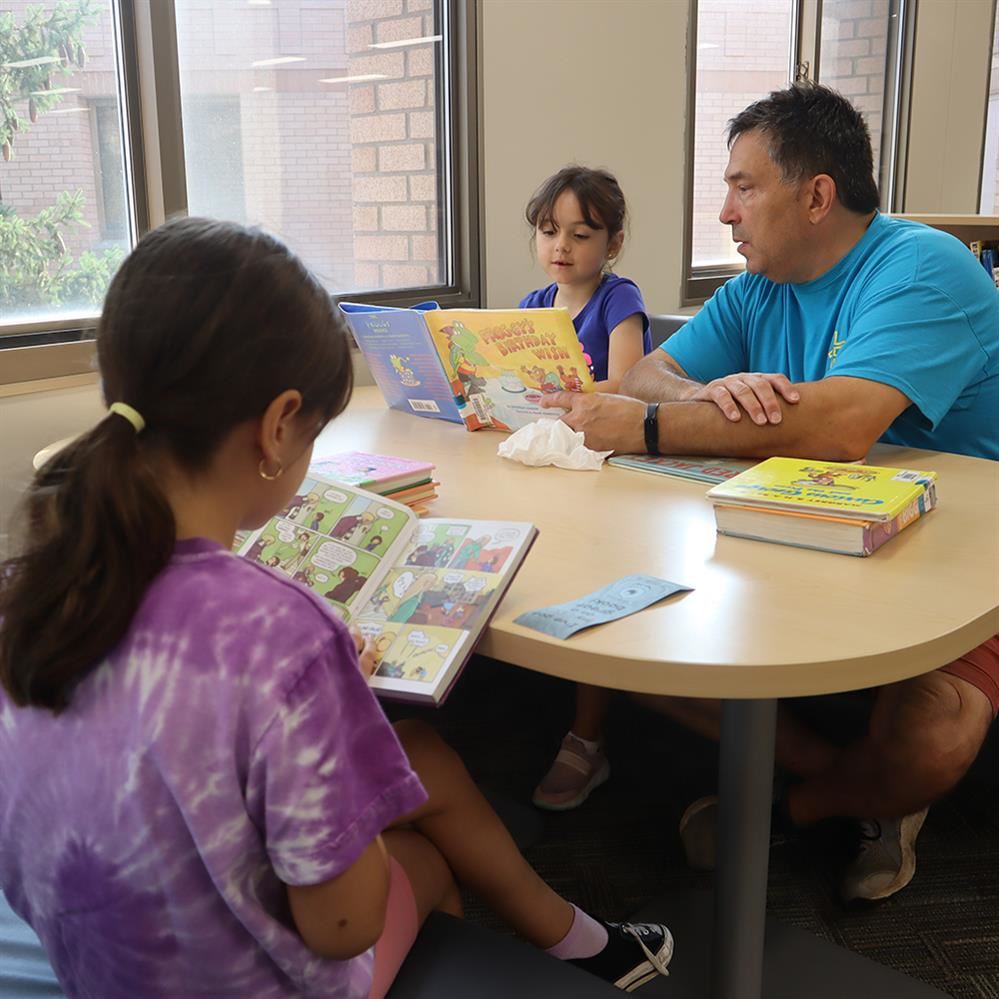  Andover Elementary students reading books with their dad during summer library hours