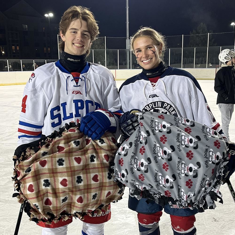  Coon Rapids High School student-athletes Andrew Clark and Tessa Boden holding donated pet beds
