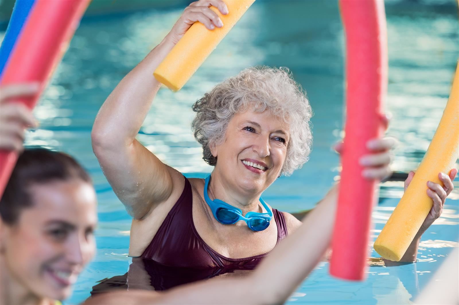 Adults exercising in pool with noodle floats. Adults exercising in pool with noodle floats.