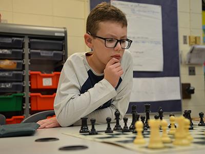 student looking intently at chess board