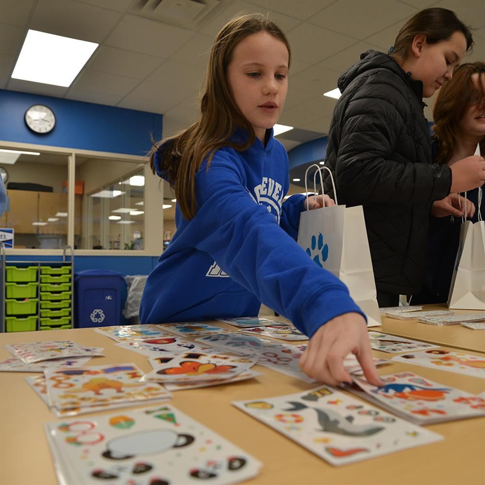  girl reaching for a sheet of stickers